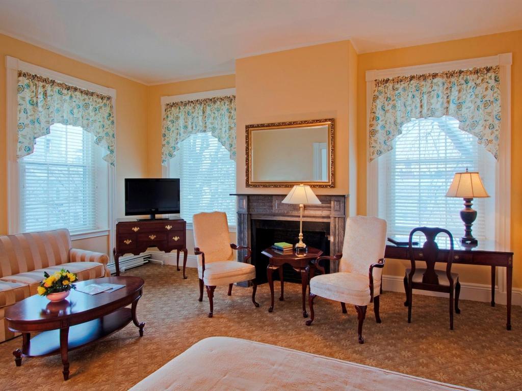 A large suite with living room furniture, an antique fireplace and a tv in the corner.