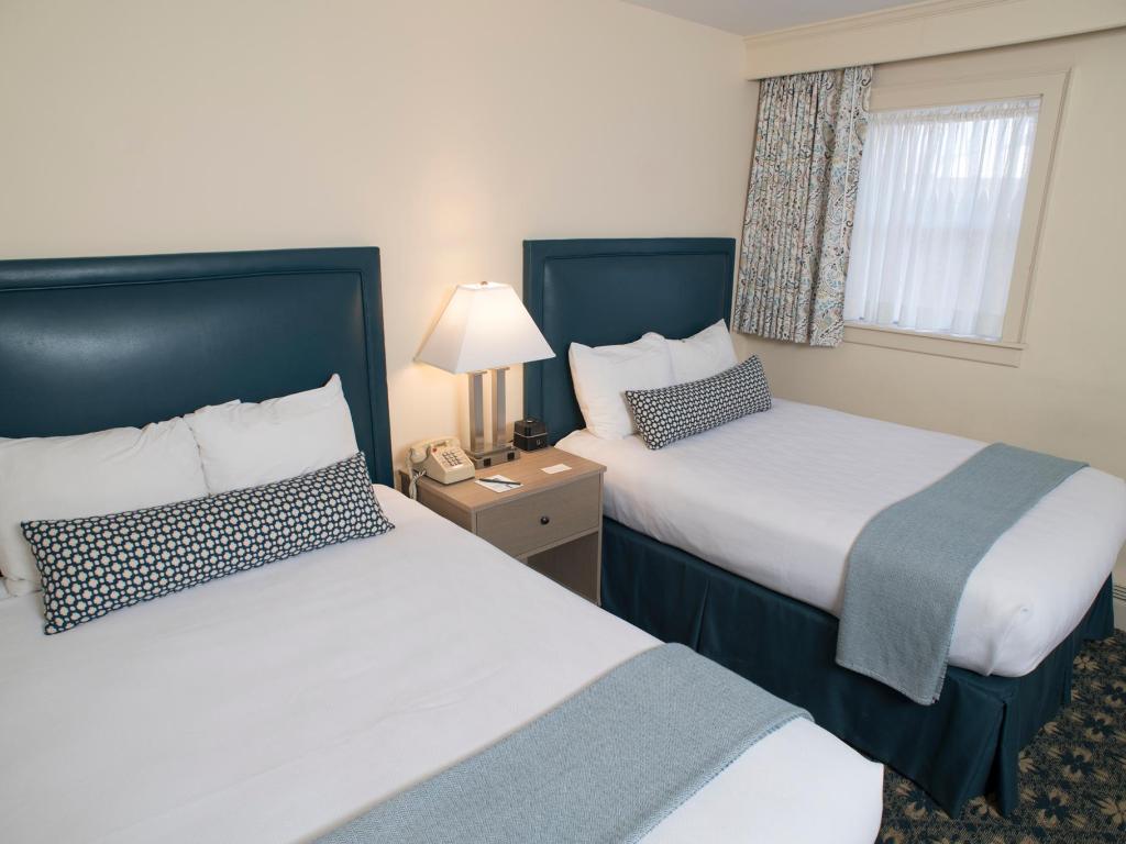 A room with two beds with blue and white bedding.