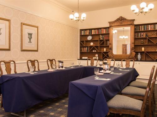 A smaller table is set up in a meeting space room with a blue tablecloth and chairs around the table.